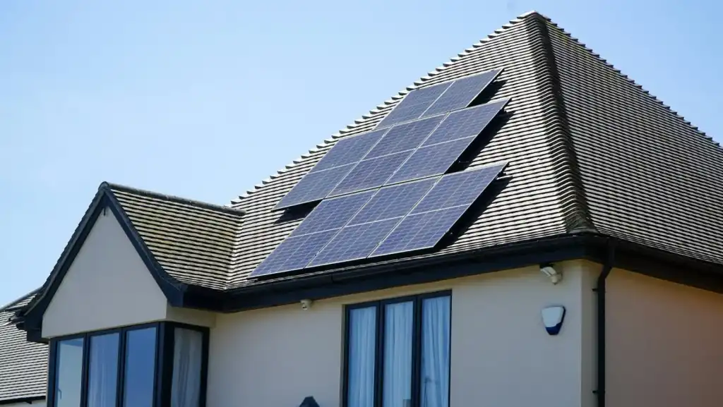 Rooftop solar panels on a suburban house under a clear blue sky